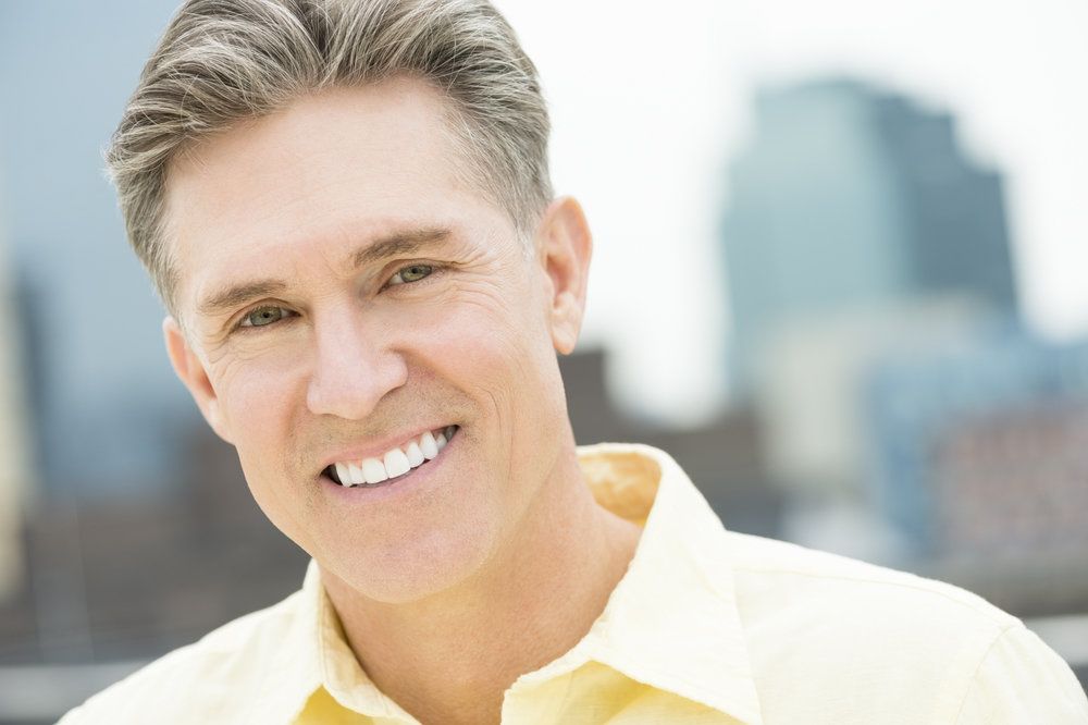 Smiling man with thick gray hair and very white teeth